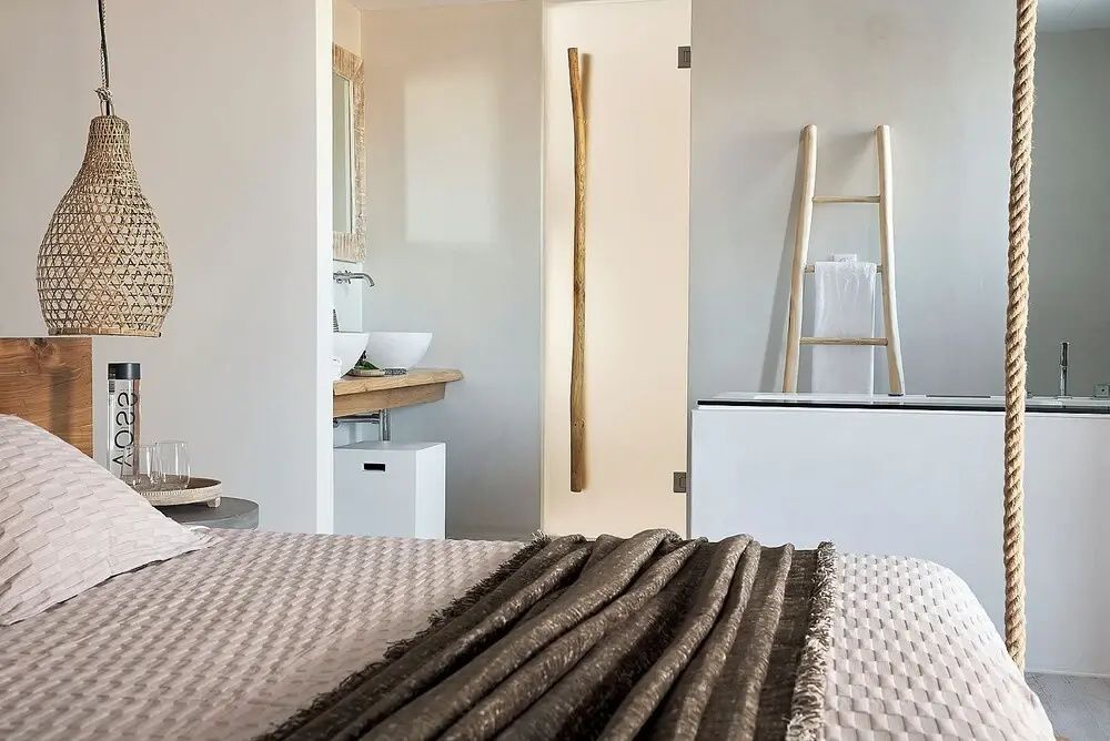 Blick vom Doppelbett auf den Badbereich mit Holzleiter und schlichtem Waschtisch.