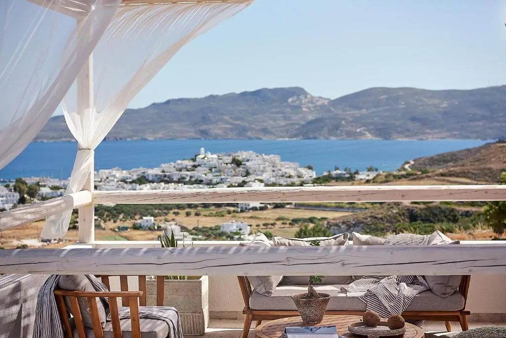 Terrassenbereich mit Sitzgelegenheiten und Weitblick auf eine Küstenstadt am Meer.