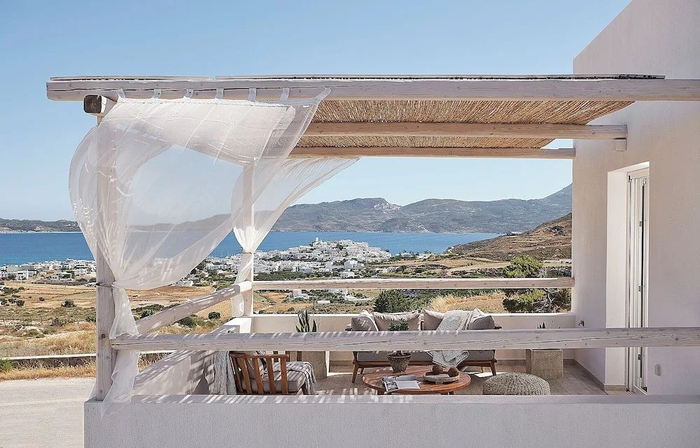 Überdachte Holzterrasse mit Sitzgelegenheiten und Panoramablick auf das Meer.