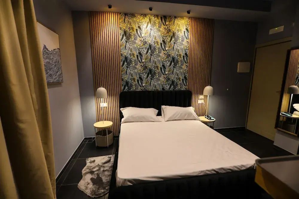 Doppelbett mit weißer Bettwäsche und dekorativer Wandverkleidung im Hotelzimmer.