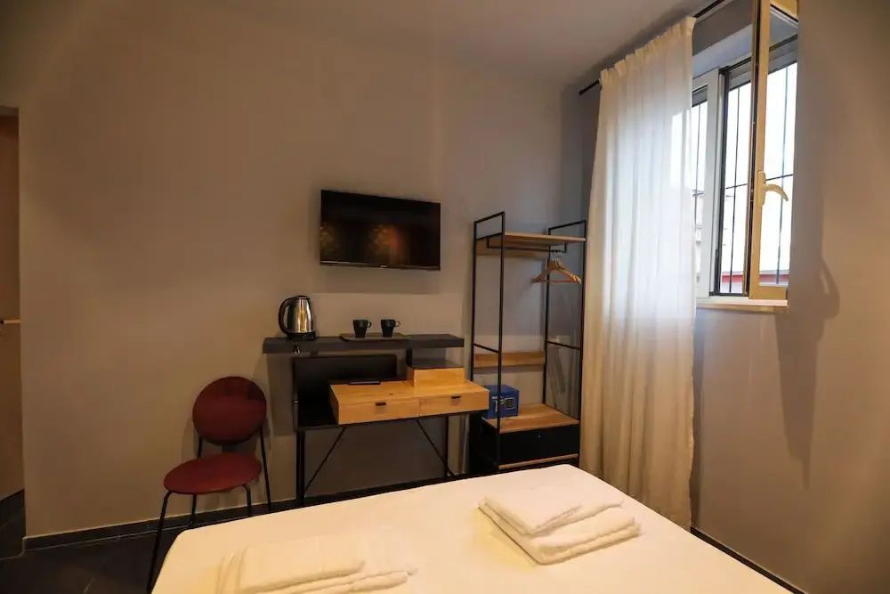 Blick in ein Hotelzimmer mit Doppelbett, offenem Kleiderschrank und Wandfernseher.