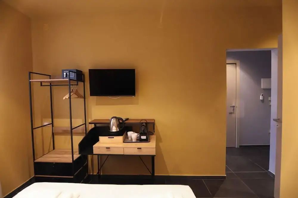 Wandbereich im Hotelzimmer mit Flachbildfernseher, Wasserkocher und Kleiderständer.