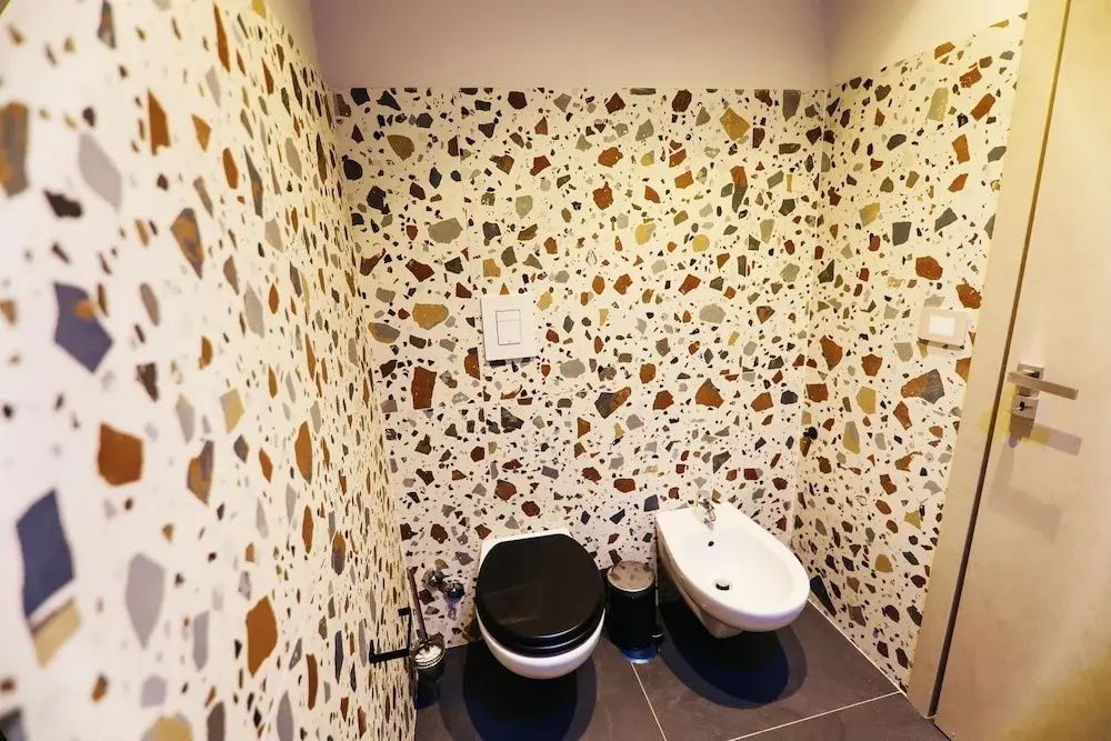 WC und Bidet in einem Badezimmer mit bunt gemusterten Terrazzofliesen.