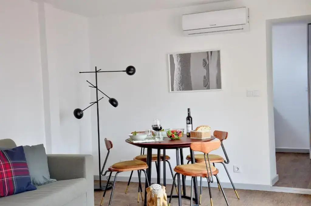 Runder Esstisch mit Holzstühlen, schwarzer Stehlampe und weißer Wand.