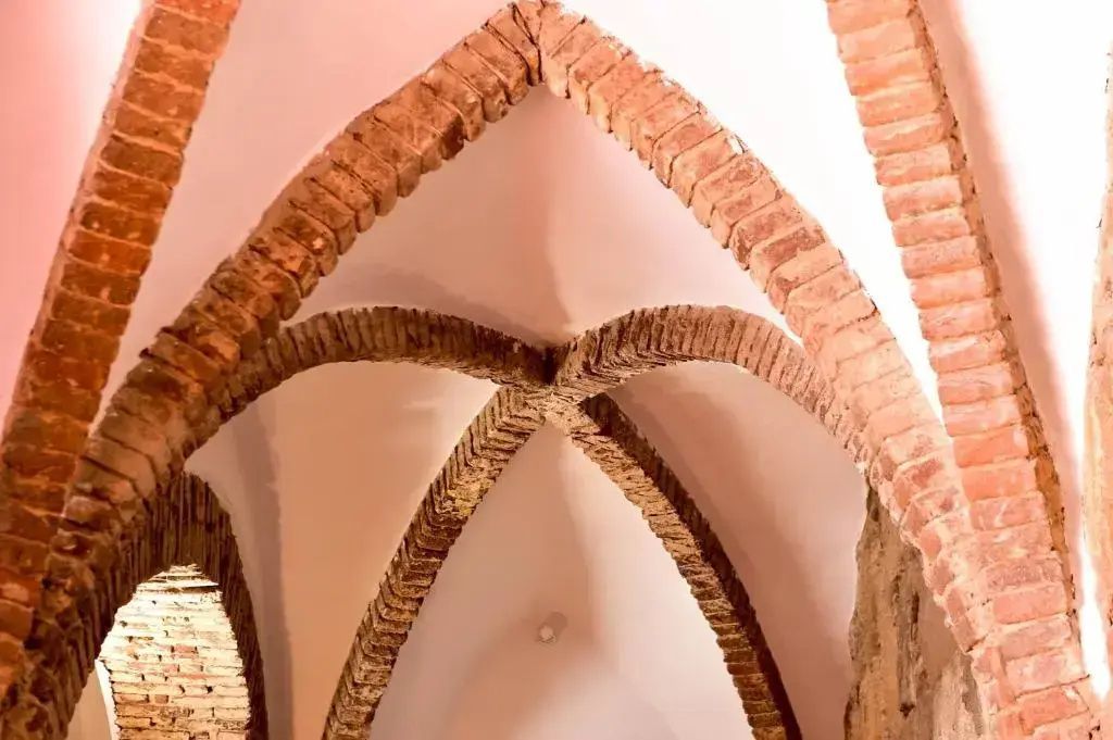 Historisches Kreuzgewölbe aus Backstein an der Decke eines Innenraums.