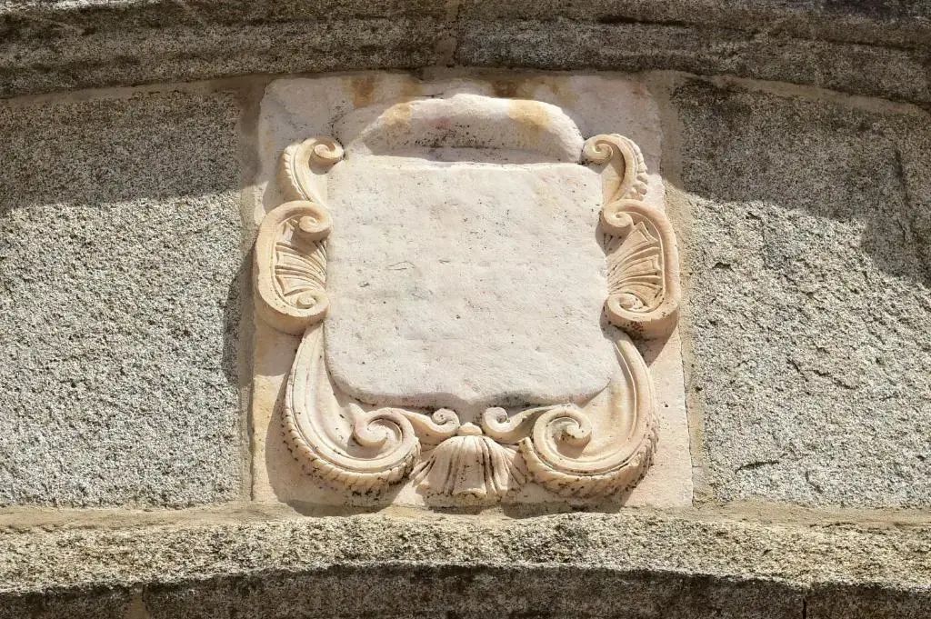 Verziertes historisches Wappen aus Stein an einer Außenwand des Gebäudes.
