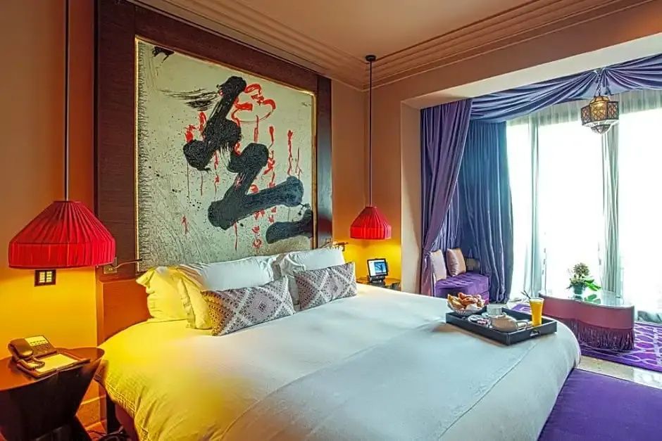 Doppelbett mit weißer Bettwäsche, großem Kunstwerk an der Wand und Frühstückstablett.