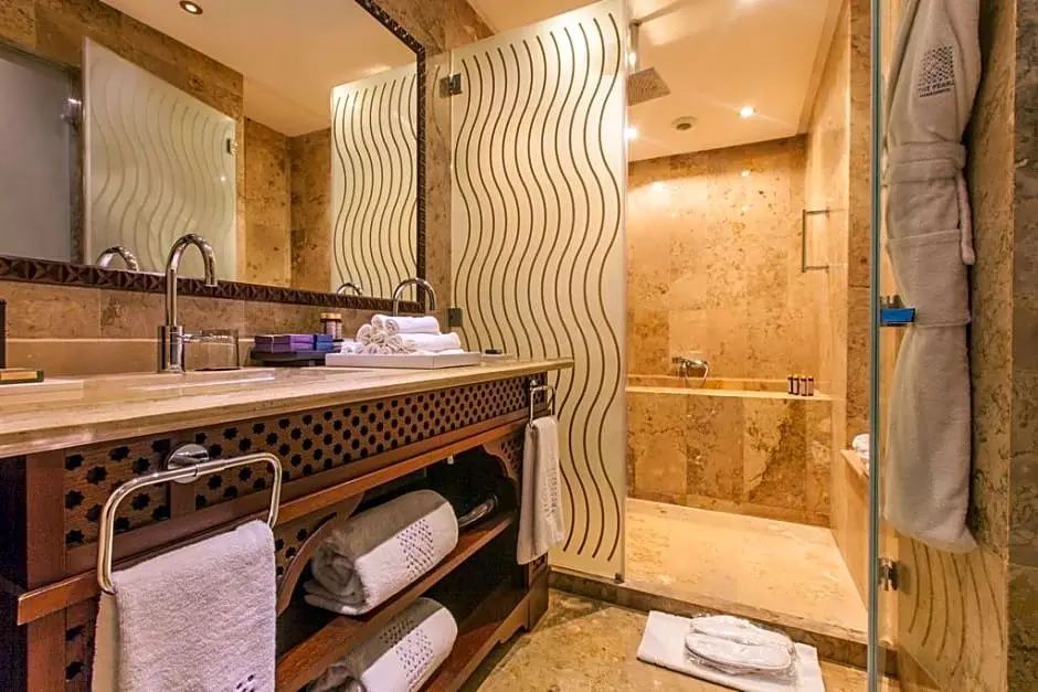 Badezimmer aus Marmor mit Holzwaschtisch, zwei Waschbecken und Duschbereich mit Glasscheibe.