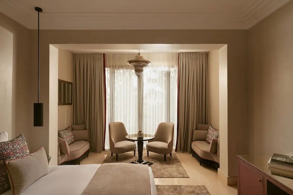 Sitzecke im Hotelzimmer mit zwei Sesselstühlen, einem kleinen Tisch und Vorhängen.