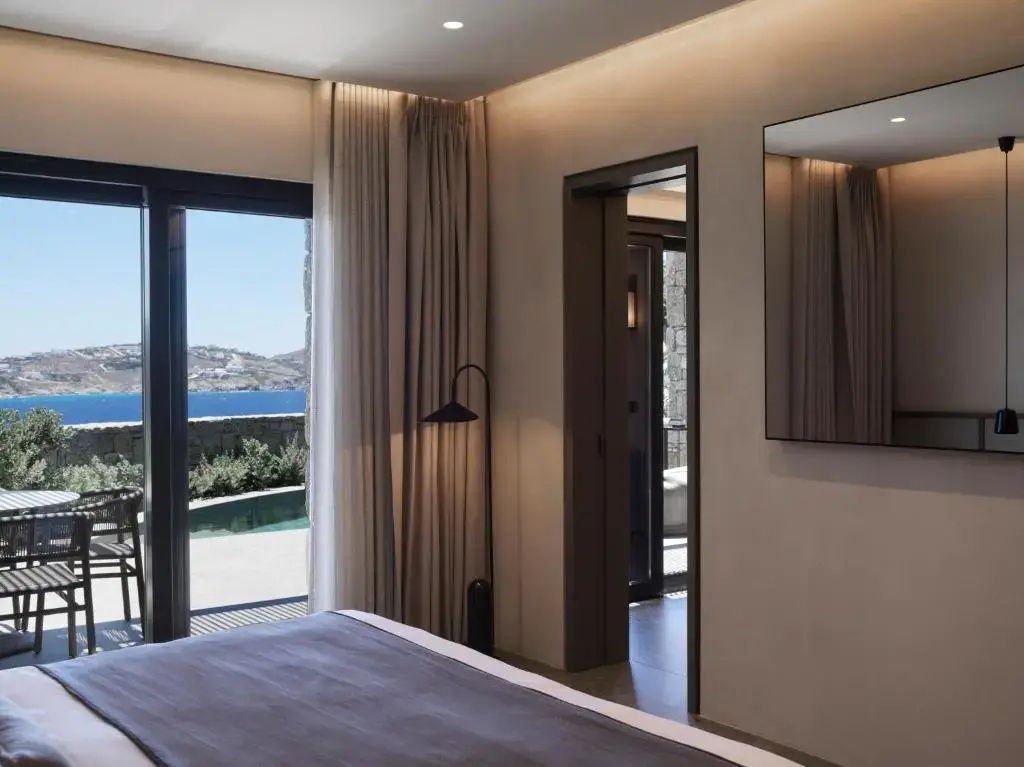 Blick aus dem Schlafzimmer auf die Terrasse mit Meerblick und blauem Himmel.