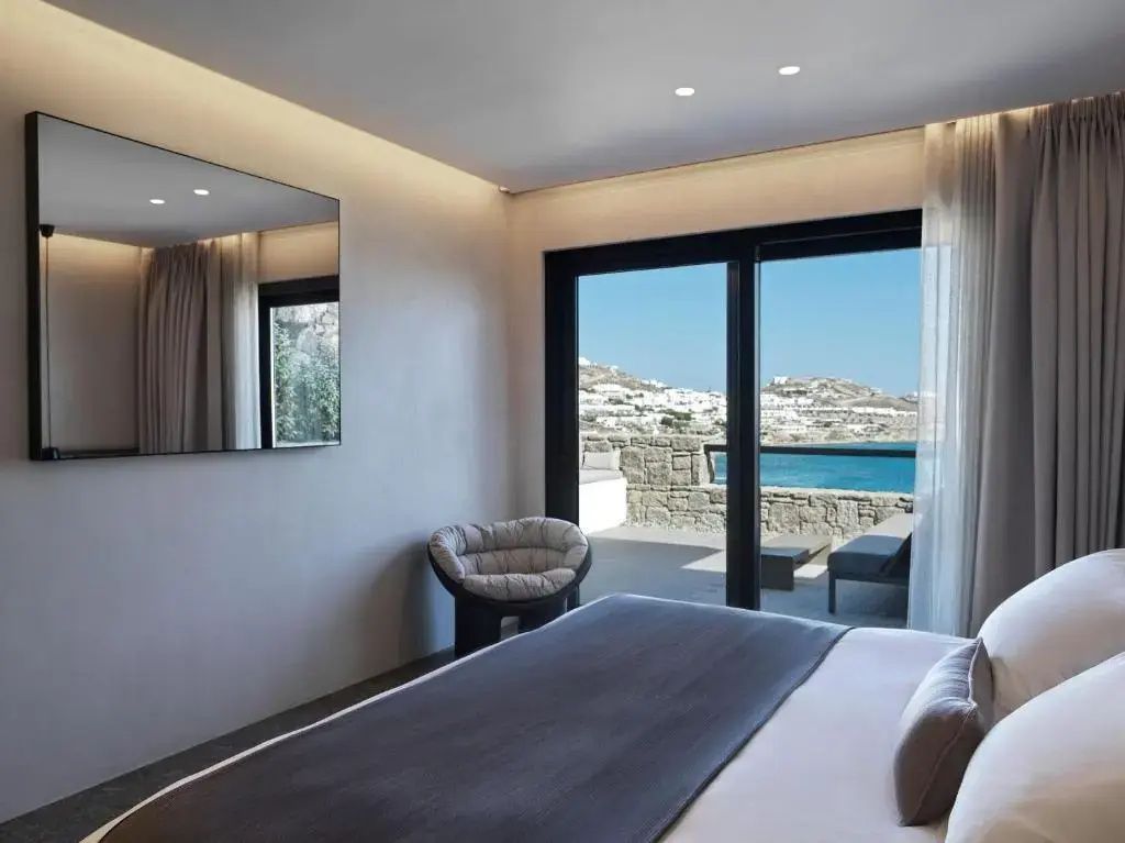 Schlafzimmer mit Blick durch die Glasschiebetür auf eine Terrasse und das Meer.