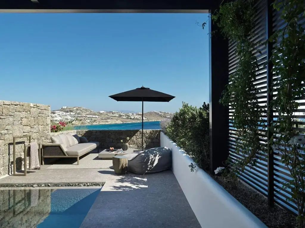 Überdachte Terrasse mit Sofa, Sonnenschirm, kleinem Pool und Aussicht auf die Küstenlandschaft.