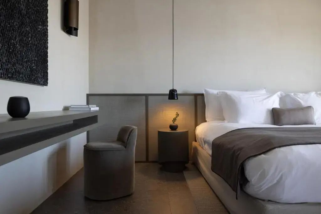Modernes Schlafzimmer mit Doppelbett, kleinem Hocker am Schreibtisch und Nachttisch.