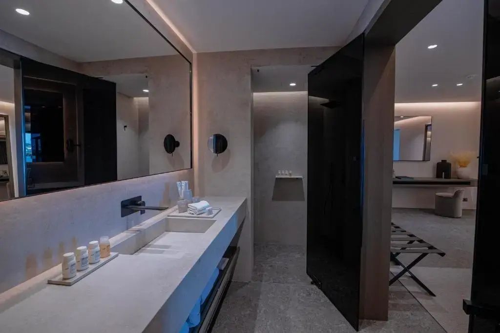 Modernes Badezimmer mit breitem Waschtisch, großem Spiegel und Duschbereich.