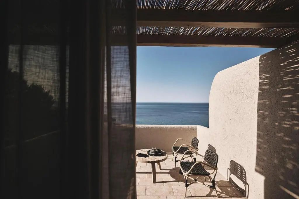 Terrasse mit zwei Stühlen und einem kleinen Tisch bietet direkten Blick auf das ruhige Meer.