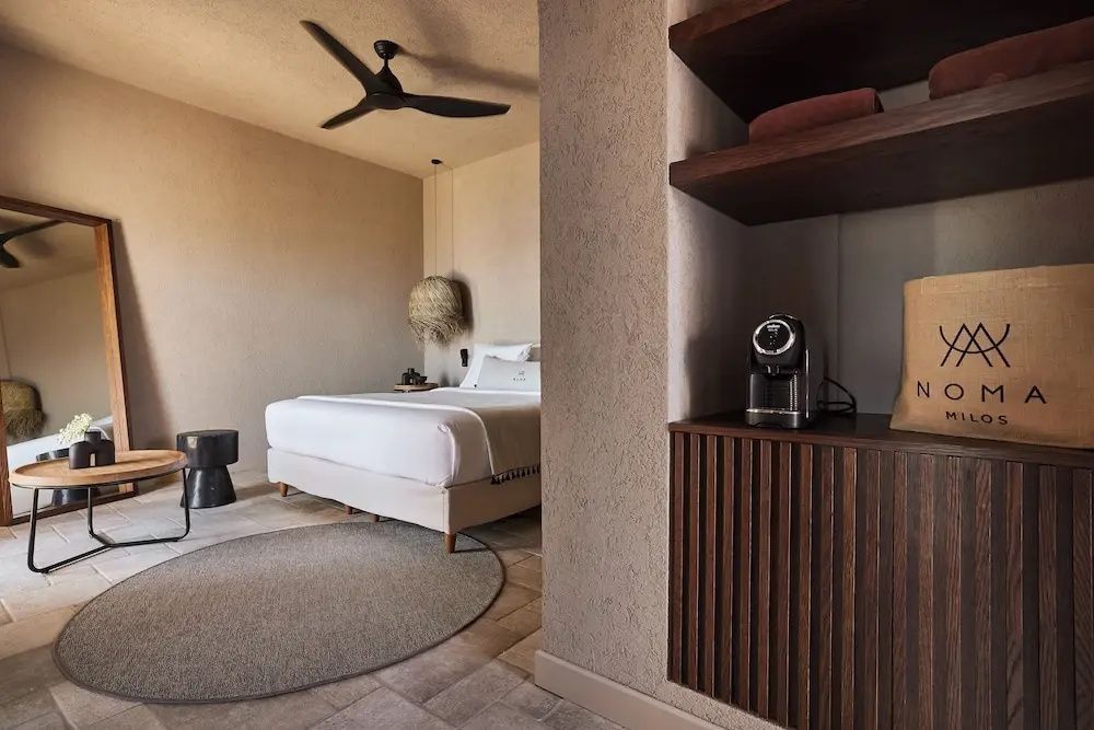 Hell eingerichtetes Schlafzimmer mit Doppelbett, Deckenventilator und rundem Teppich.