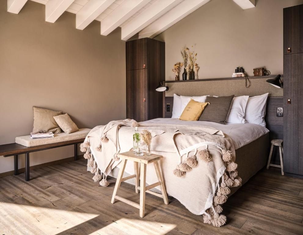 Doppelbett mit Decken und Kissen in einem hellen Zimmer mit Holzdecke und Holzboden.