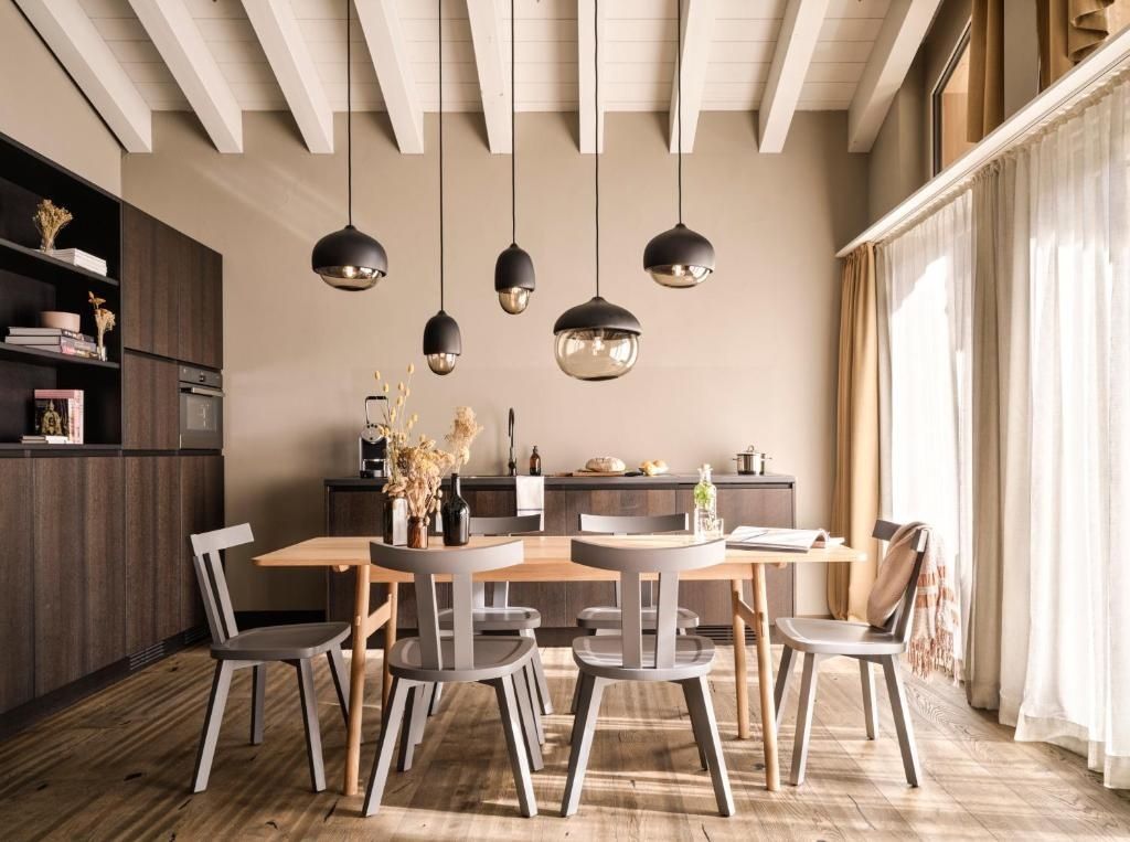Esstisch aus Holz mit grauen Stühlen und modernen Hängelampen unter einer Holzdecke.