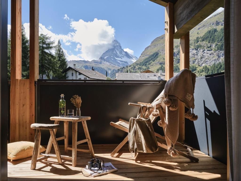 Balkon mit Holzstühlen und direktem Blick auf das schneebedeckte Matterhorn.