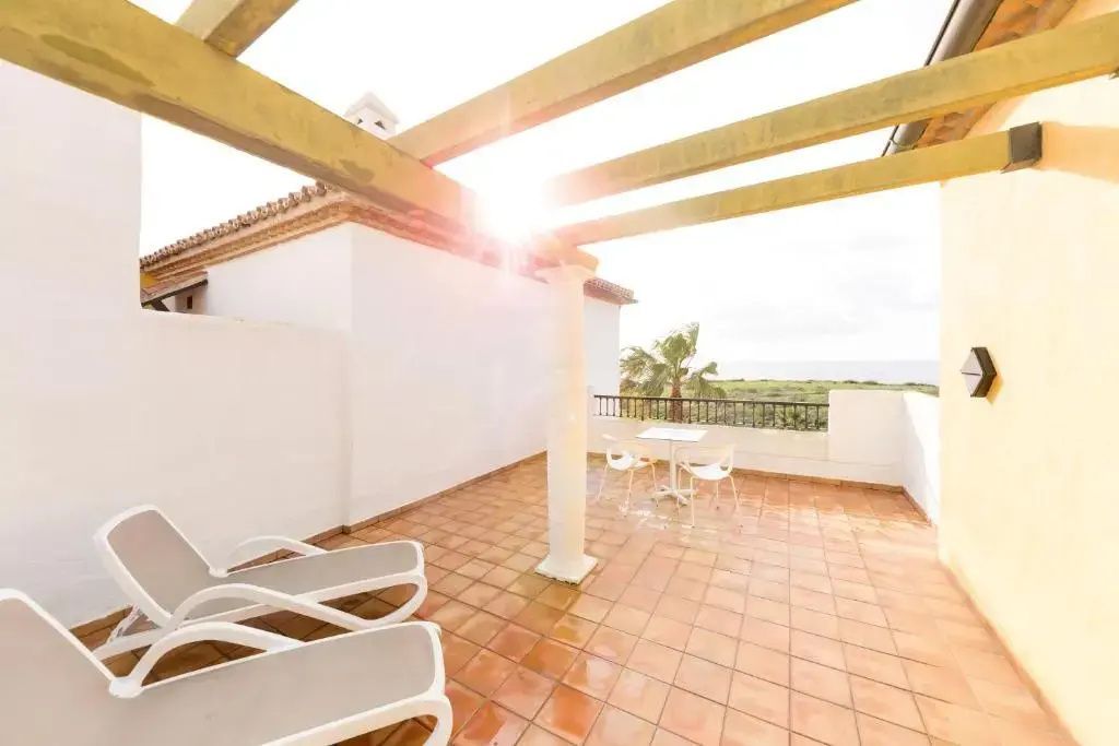 Terrasse mit Fliesenboden, Pergola, Sonnenliegen und Blick auf die umliegende Landschaft.