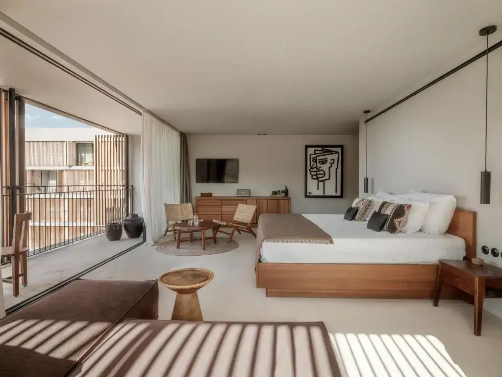 Geräumiges Hotelzimmer mit großem Doppelbett, Sitzecke und angrenzendem Balkon.