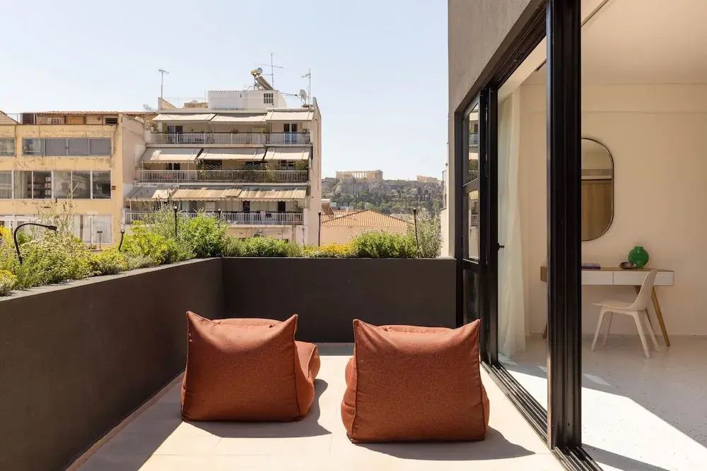 Blick von der Terrasse mit Sitzkissen auf die umliegende Stadt und die Akropolis.