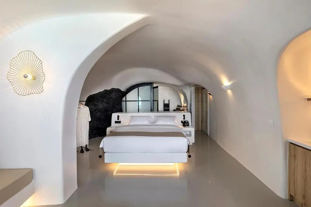 Modernes Höhlenschlafzimmer in Weiß mit indirekt beleuchtetem Doppelbett.