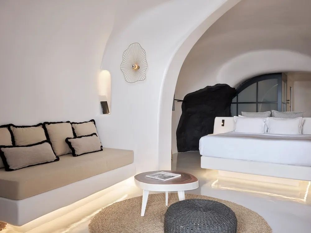 Heller Wohnbereich einer Suite mit eingebauter Sitzbank, Couchtisch und Blick auf das Bett.