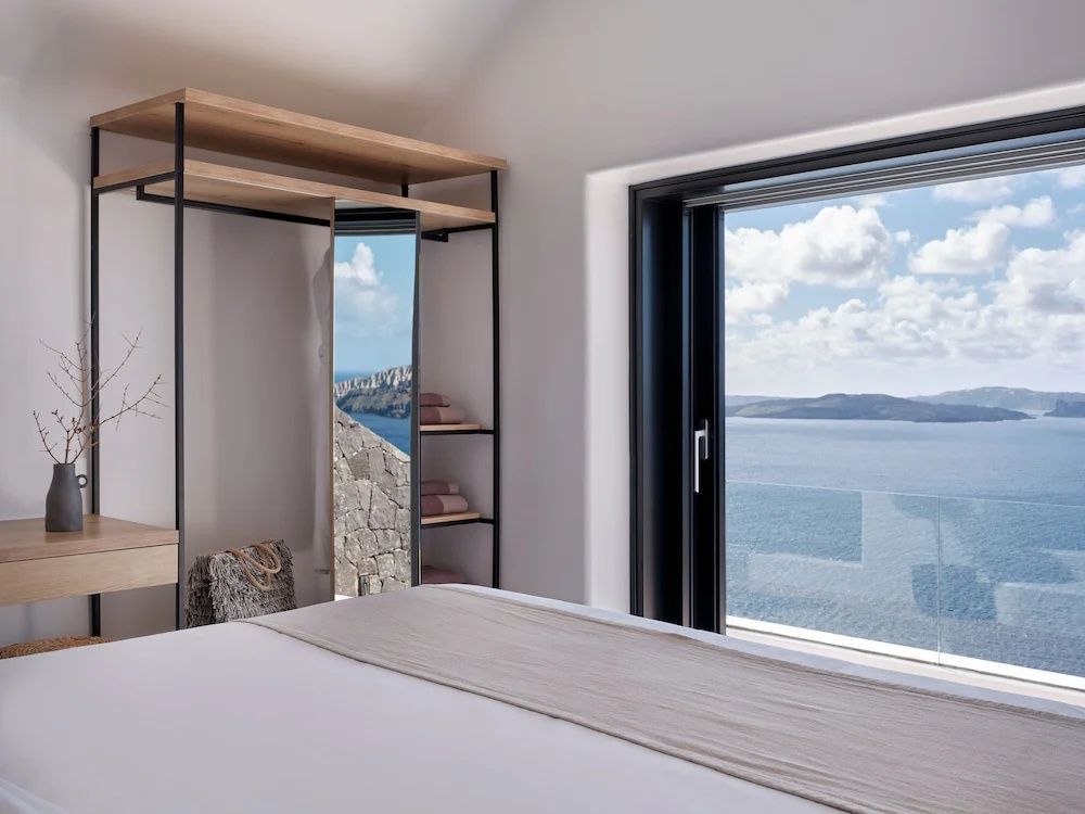 Blick aus dem Hotelzimmer durch eine große Tür auf das Meer und die vulkanische Landschaft.