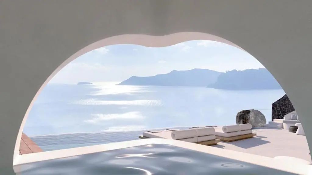Blick durch einen Rundbogen auf einen Pool, Sonnenliegen und das Meer.