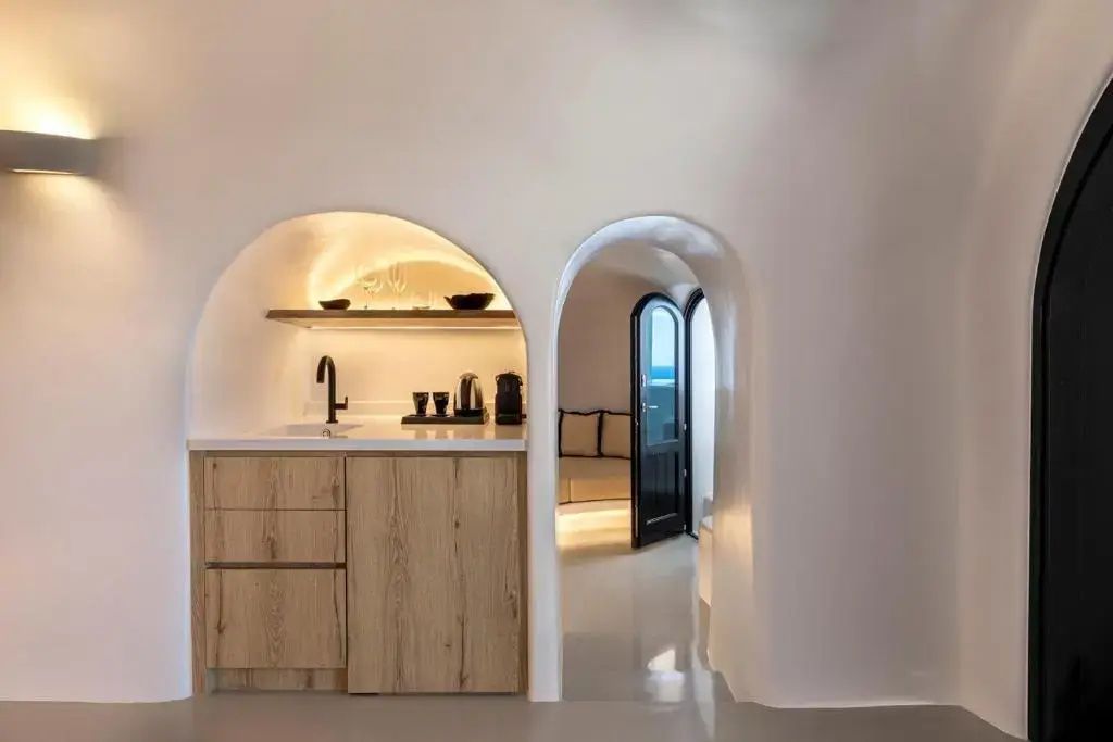 Kleine Küchennische in weißer Höhlenarchitektur mit Blick in den Wohnbereich.
