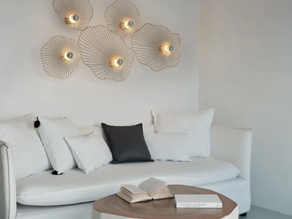 Sitzbereich mit weißer Couch, Holztisch und dekorativen Lampen an der Wand.