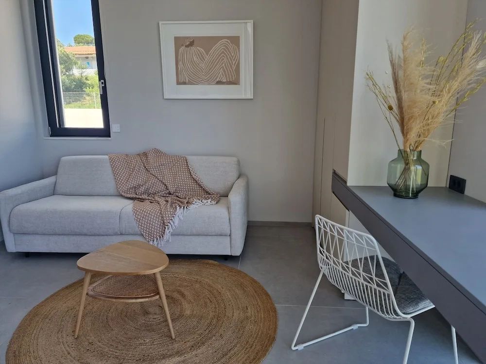Helles Wohnzimmer mit beigem Sofa, rundem Teppich, kleinem Holztisch und Bild.