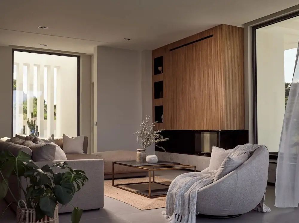Wohnzimmer mit beigen Polstermöbeln, Couchtisch und Wandverkleidung aus Holz.