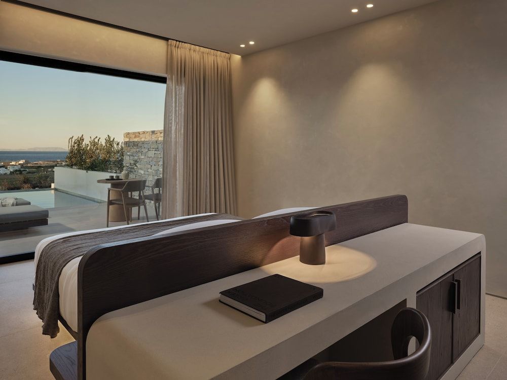 Hotelzimmer mit Schreibtisch hinter dem Bett und Blick auf die Terrasse.