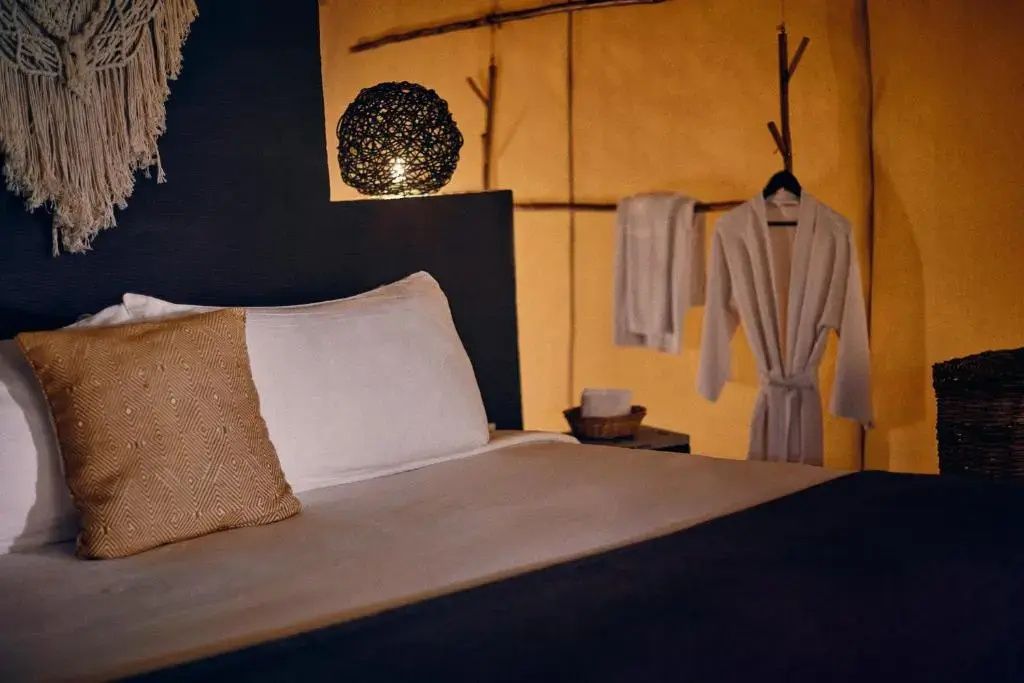 Ein Doppelbett mit weißer Bettwäsche sowie ein Bademantel an einem Garderobenständer.