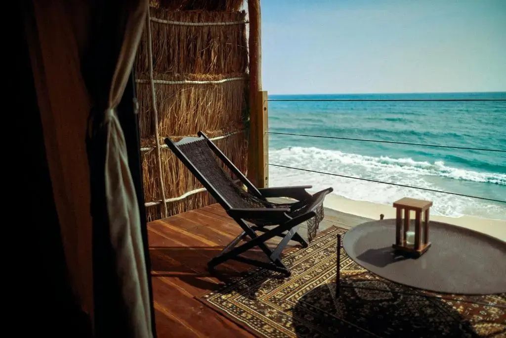 Private Holzterrasse mit einem Klappstuhl und freiem Blick auf das Meer.