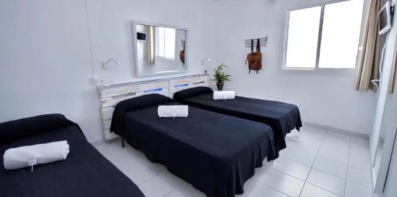 Schlafzimmer mit zwei Einzelbetten, schwarzen Tagesdecken, weißem Kopfteil und Spiegel.