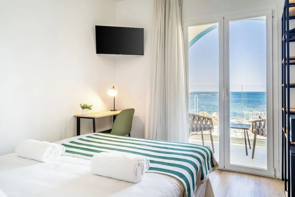 Hotelzimmer mit Schreibtisch, Wandfernseher und direktem Zugang zum Balkon mit Meerblick.