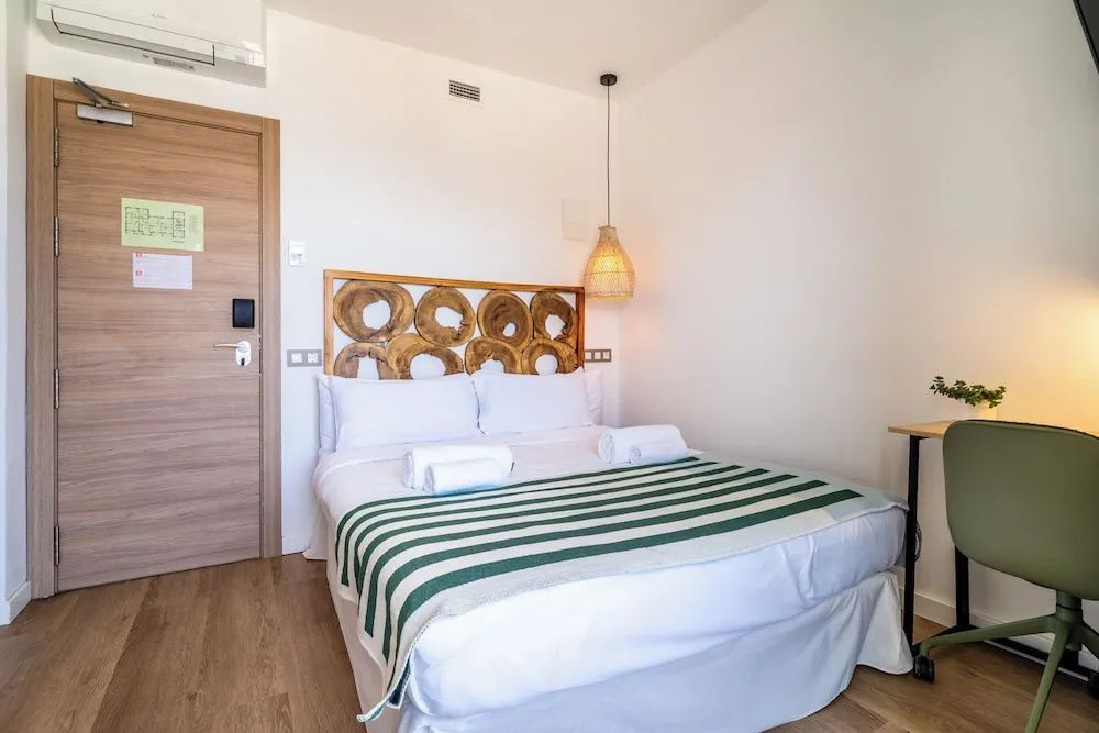 Ein eingerichtetes Hotelzimmer mit Doppelbett, Parkettboden und Naturholzelementen.