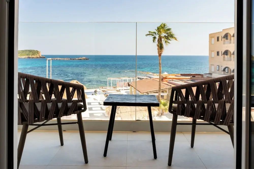 Balkon mit zwei dunklen Sesseln und einem kleinen Tisch mit freiem Blick auf das blaue Meer.