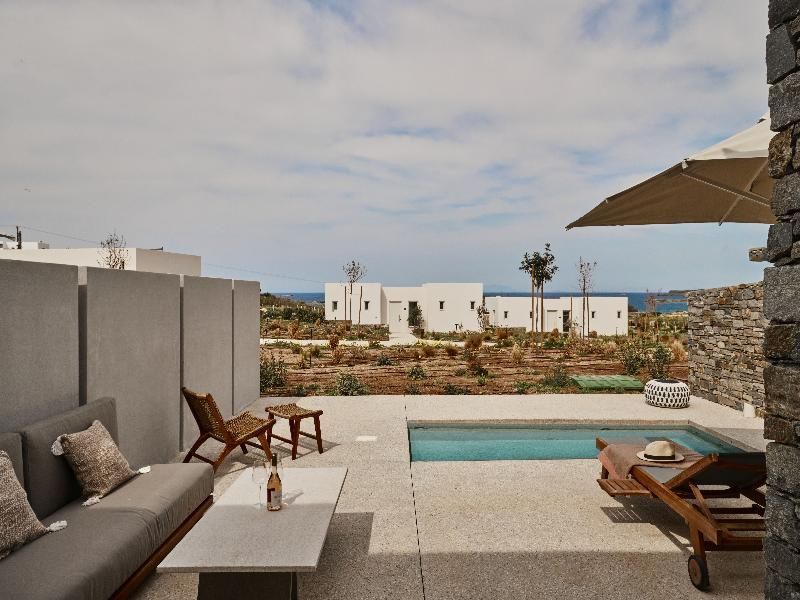 Terrasse mit privatem Pool, Sonnenliegen und Blick auf weiße Gebäude und das Meer.