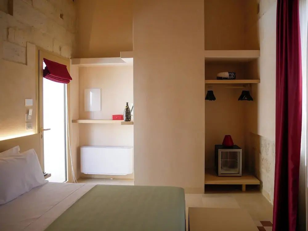 Einbauregale und ein kleiner Kühlschrank in einem Hotelzimmer mit hellen Sandsteinwänden.