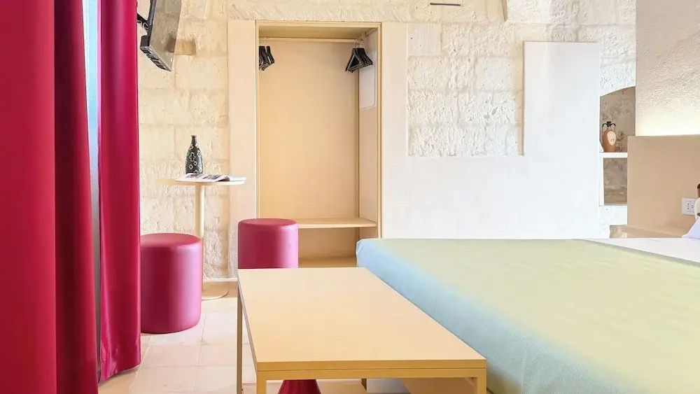 Einrichtung im Zimmer mit hellen Holzmöbeln, zwei roten Hockern und offener Garderobe.