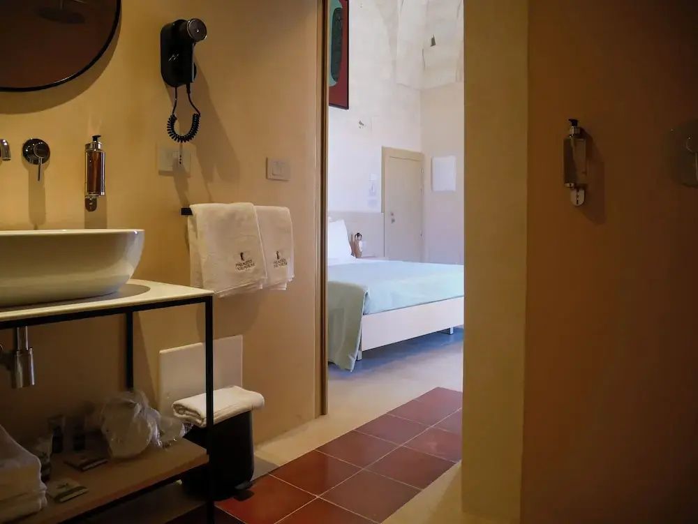 Blick vom Badezimmer mit Waschtisch in das angrenzende Schlafzimmer mit Doppelbett