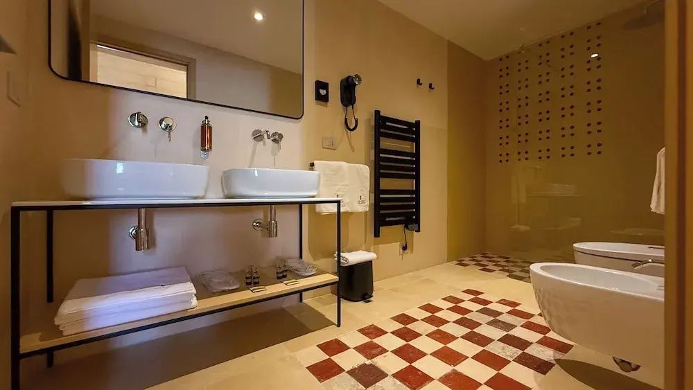 Modernes Badezimmer mit zwei Waschbecken auf einem Metallgestell, Wandspiegel und Heizkörper.