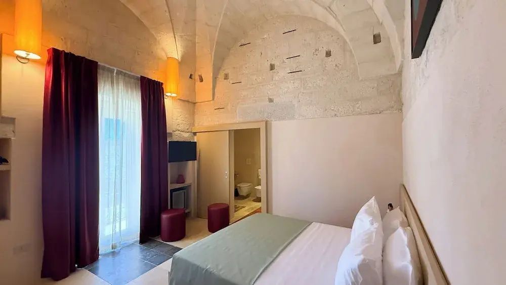 Schlafzimmer mit historischem Steingewölbe Doppelbett und roten Vorhängen
