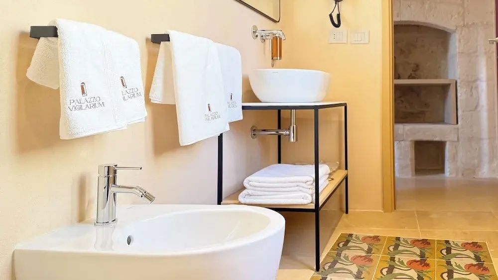 Badezimmer mit modernem Waschtisch, Handtüchern und Bidet bei warmer Wandbeleuchtung.