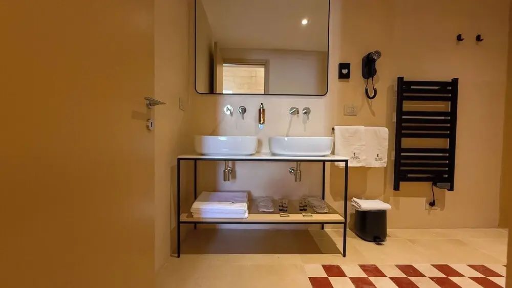 Doppelwaschtisch mit zwei weißen Aufsatzbecken, Wandarmaturen und großem Spiegel im Badezimmer.
