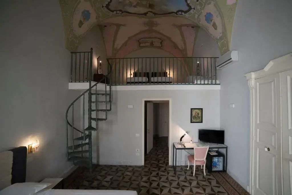 Zimmer mit Wendeltreppe zu einer Schlafempore unter einer bemalten Gewölbedecke.